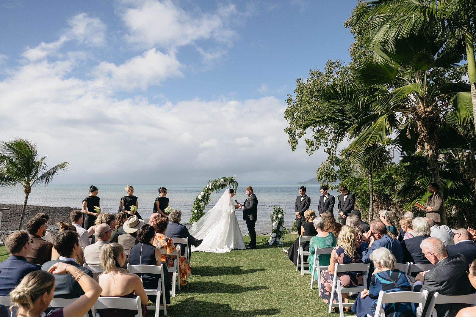 Bride and Groom at wedding ceremony with ocean in the background and guests seated in front